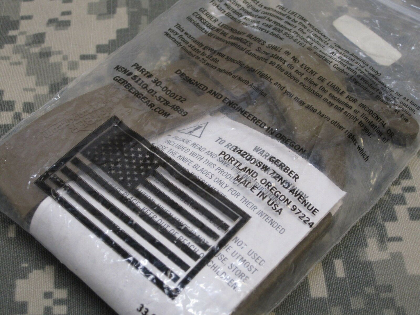 US military issue Gerber coyote brown strap cutter and seat belt hook knife with Army OCP camouflage pattern.