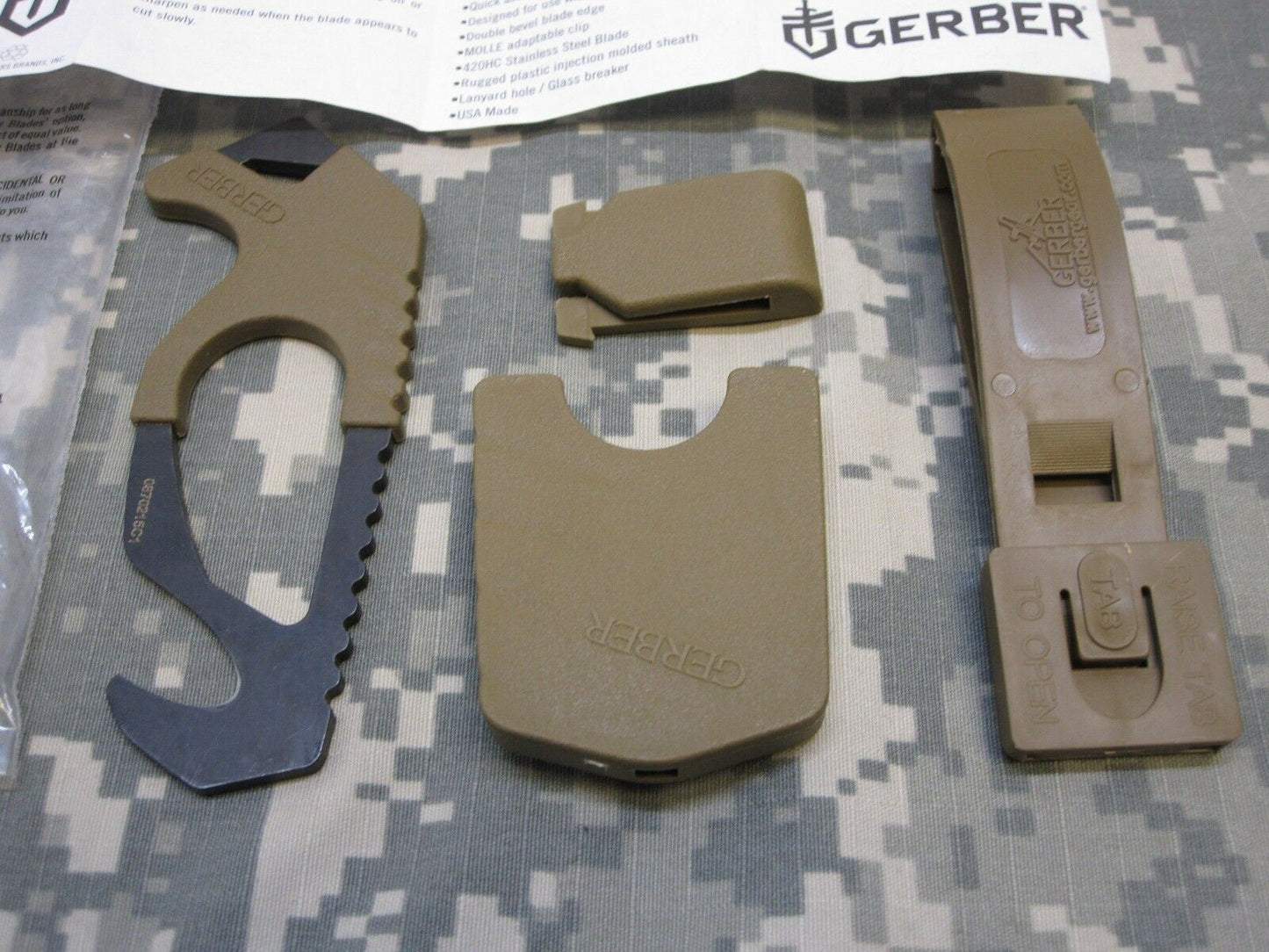 US military issue Gerber coyote brown strap cutter and seat belt hook knife in Army OCP camouflage, with ergonomic handle and blade.