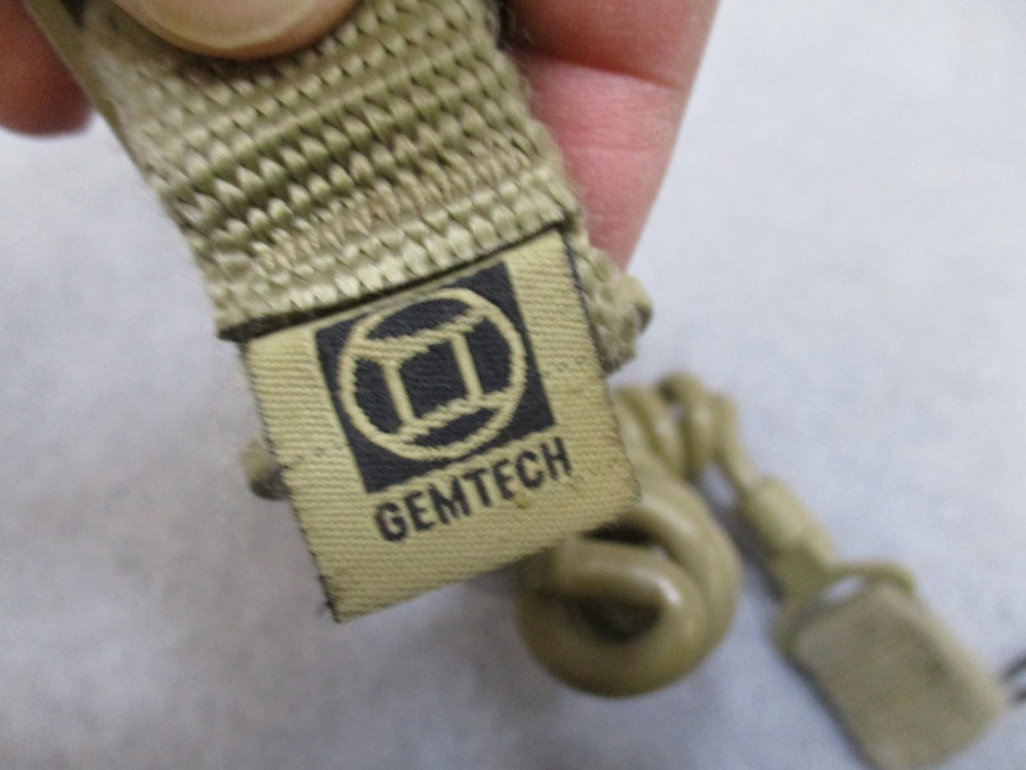 Tan coiled Gem-Tech pistol lanyard dummy cord for tactical duty gear, designed for secure firearm retention by Centex Military Gear.