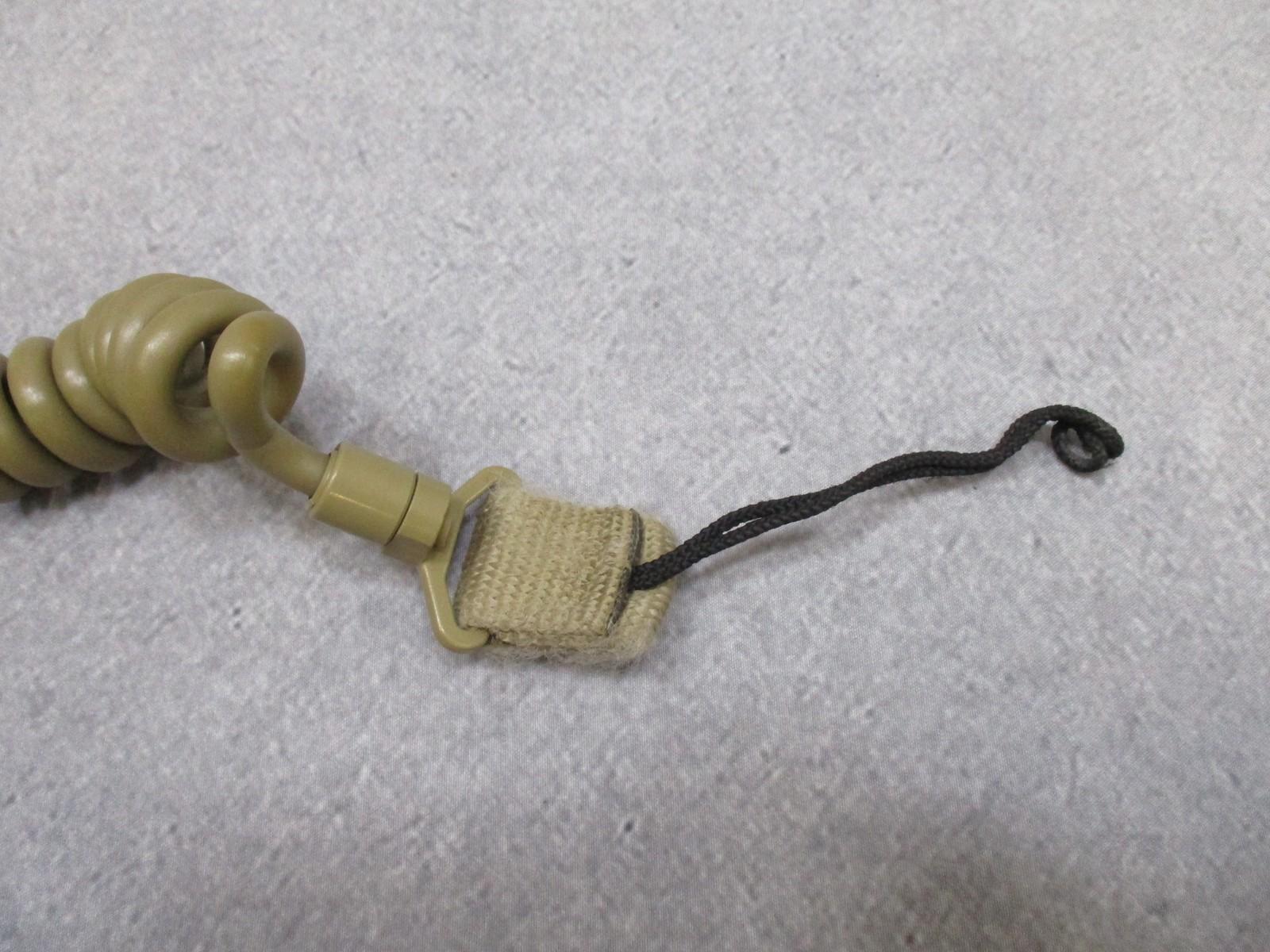 Coiled tan Gem-Tech pistol lanyard dummy cord for tactical duty gear, designed for secure firearm attachment by Centex Military Gear.