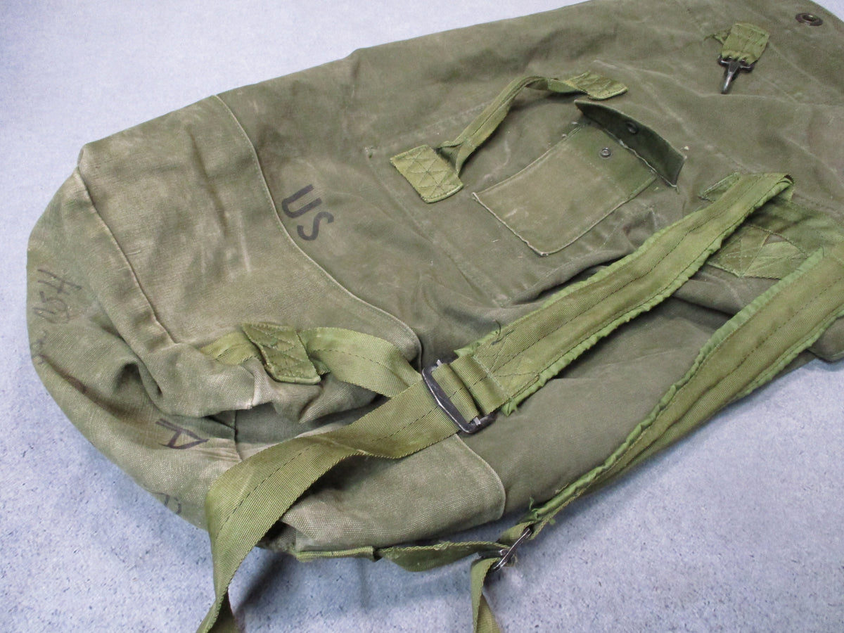 USGI 1980s OD green cotton canvas duffel sea bag with military surplus wear, rugged and used for military or outdoor use.