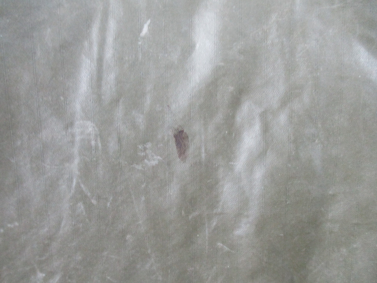 German Bundeswehr military poncho in OD green, used rain cape with shelter design, shown laid flat on a surface.