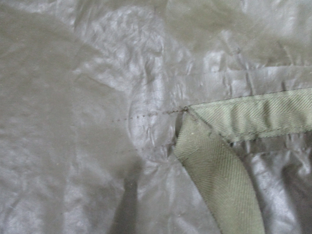 German Bundeswehr military poncho in OD green, used rain cape with shelter features, displayed laid out flat.