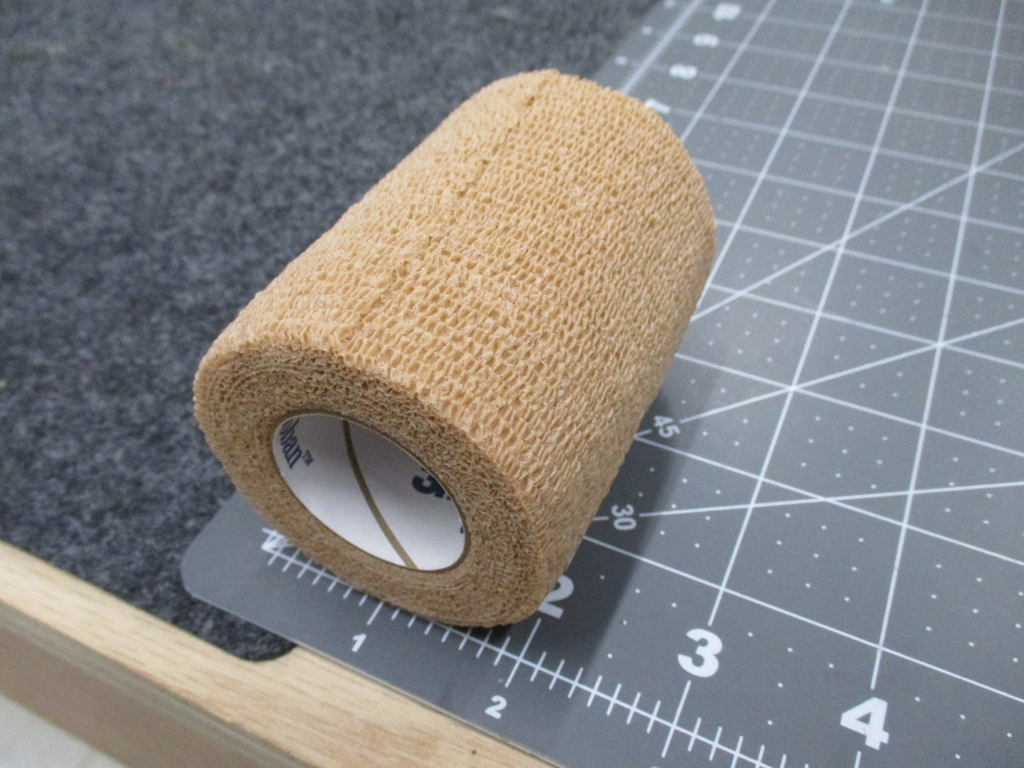 3M Coban self-adherent wrap in tan, 3 inches by 5 yards, showing flexible stretch tape for medical and athletic use.
