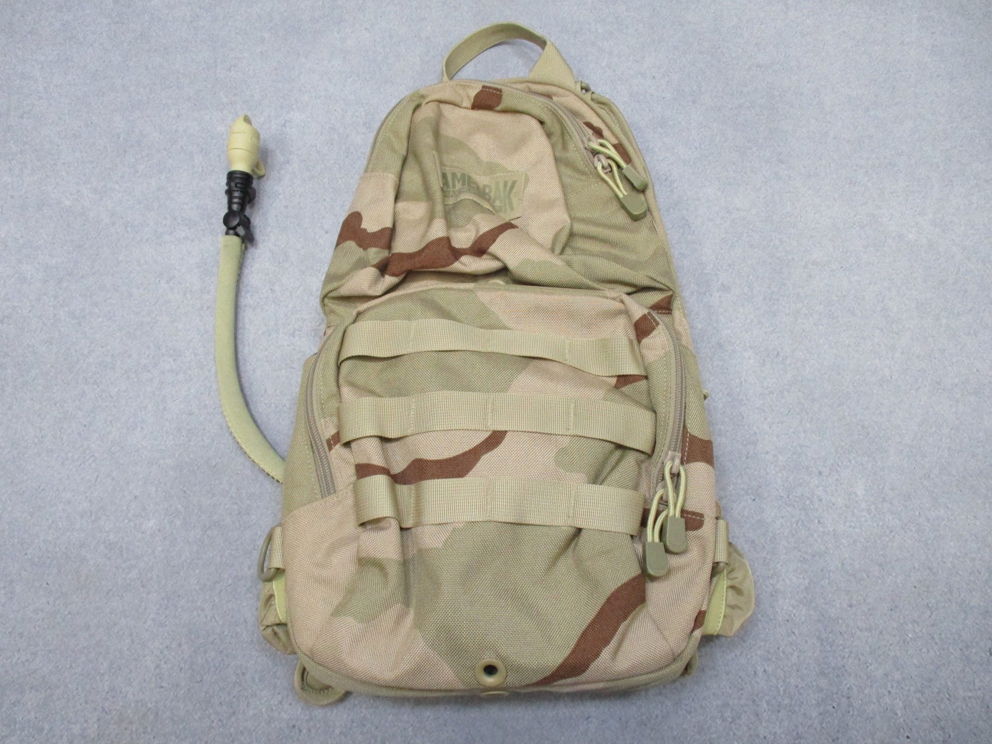 CamelBak MULE hydration pack in desert tan with tactical design and hydration carrier, shown with adjustable straps and multiple compartments.