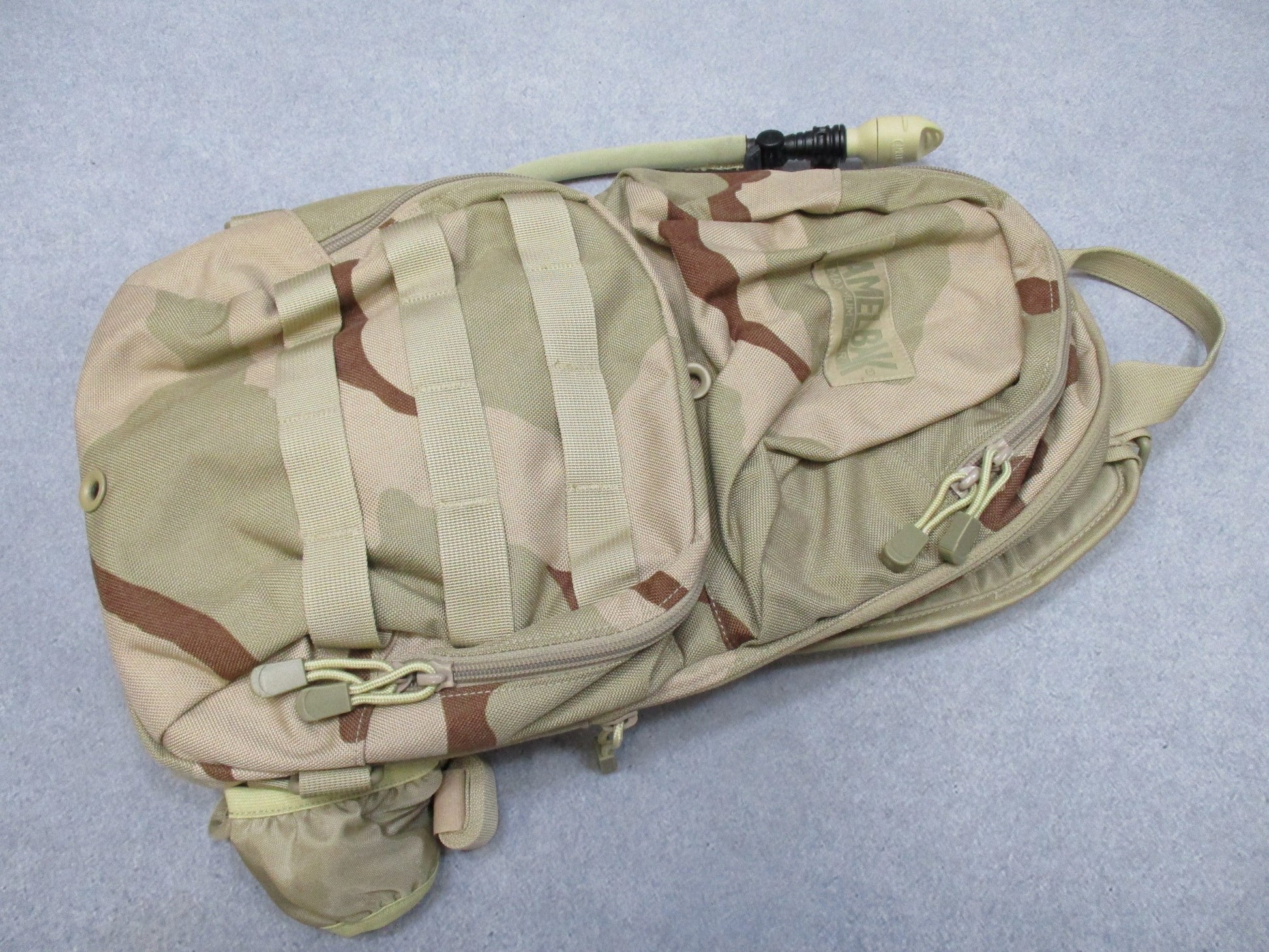 CamelBak MULE hydration pack in desert tan with tactical design, featuring a hydration carrier and multiple compartments.