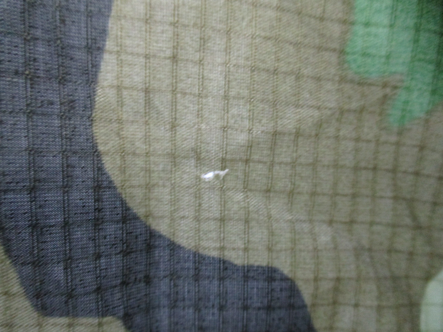 USGI military rain poncho in woodland camouflage, ripstop fabric, lightweight and durable for outdoor rain protection.