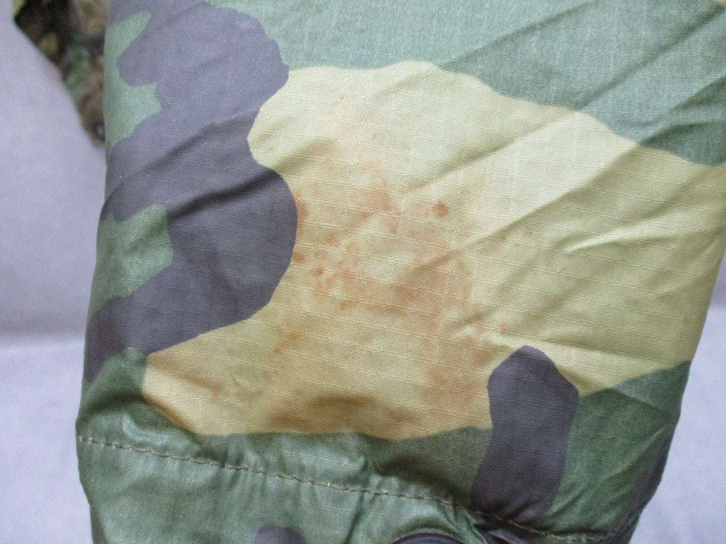 USGI military rain poncho in woodland camo ripstop fabric, made by Centex Military Gear, with hood and button closures.