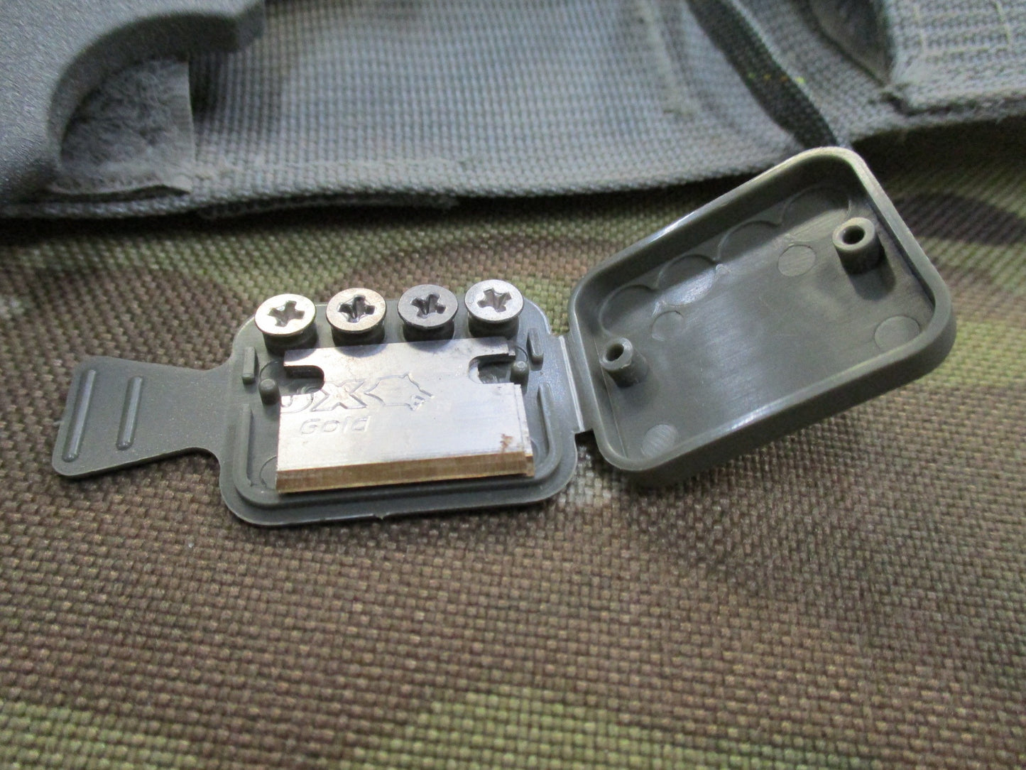 Used Ontario Knife strap and seat belt cutter with sheath, foliage-patterned parachute knife for survival and rescue tasks.
