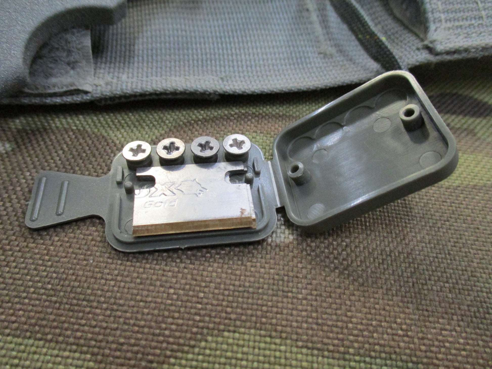 Used Ontario Knife strap and seat belt cutter with sheath, foliage-patterned parachute knife for survival and rescue tasks.