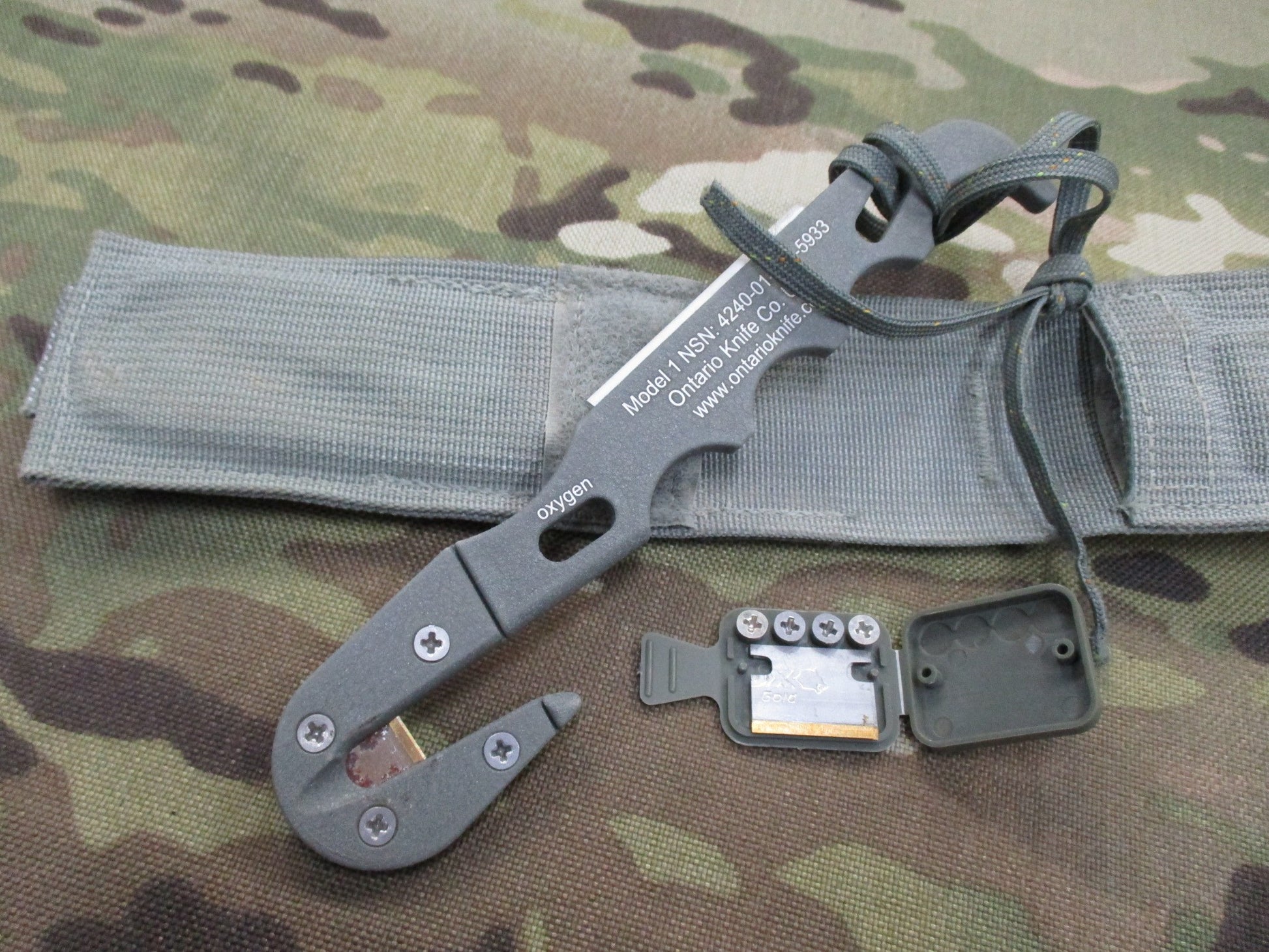 Used Ontario Knife Strap/Seat Belt Cutter with sheath, foliage camouflage design, military-style parachute knife by Centex Military Gear